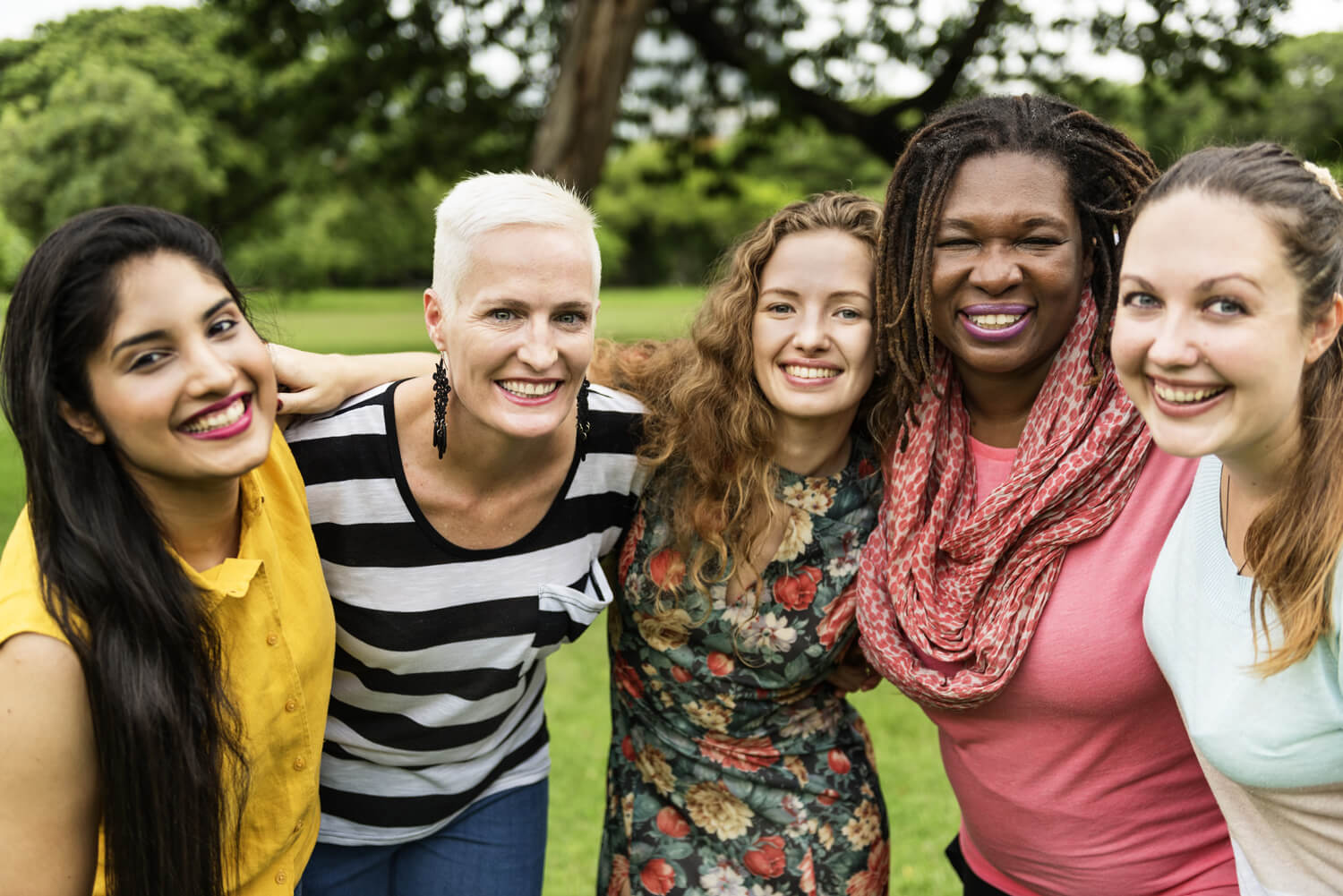 Diverse group of women smiling with their arms around each other